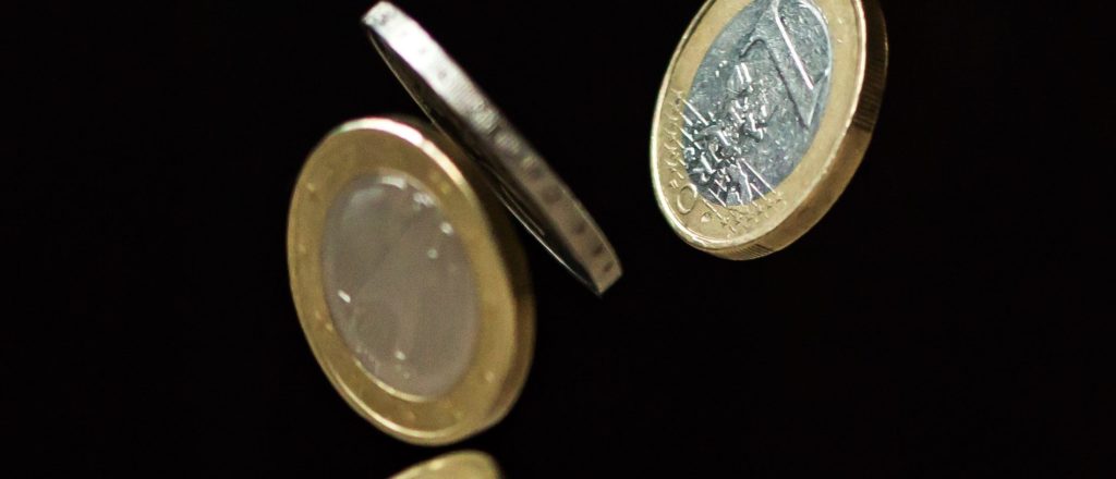 1-Euro-Münzen fallen auf einen Holztisch