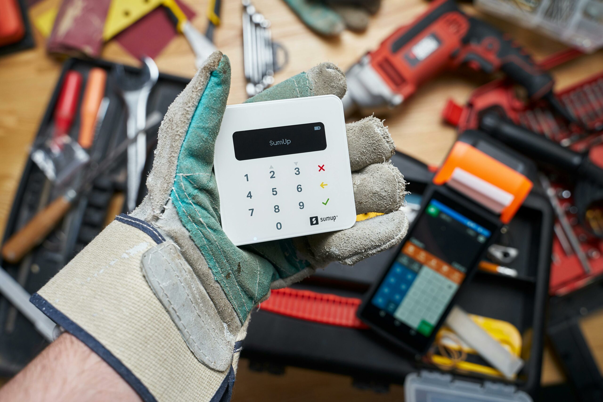 Bild, auf dem ein elektronisches Kassensystem zu sehen ist, welches von einer Hand im Handschuh gehalten wird